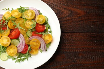Fresh salad with yellow tomatoes on wooden table, top view. Space for text