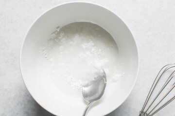 Overhead view of icing sugar mixed with water, powdered sugar dissolved in water on a white table