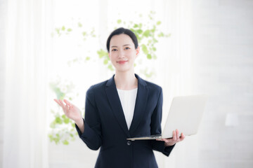 ノートパソコンを持つビジネスウーマン　カメラ目線でオススメのポーズ