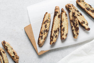 Overhead view of chocolate chip biscotti on white parchment lined tray, top view of chocolate chip cantucci cookies on a white board