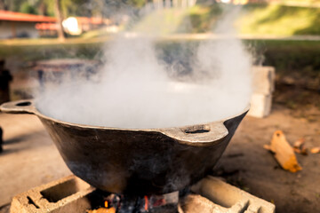 Metal saucepan with boiling water, over a campfire.