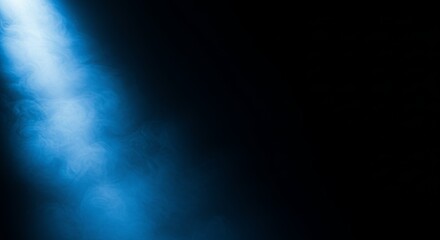 Fototapeta premium Soft blue light beam illuminating swirling mist against a dark background, creating a mysterious and ethereal atmosphere