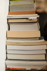 close-up of a stack of used books in a variety of sizes against an off-white wall in an interior