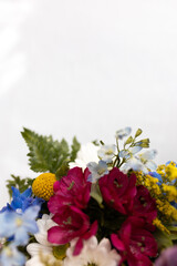 close-up of a spring floral bouquet in pinks, yellows, whites and blues against a soft white background with copy space 