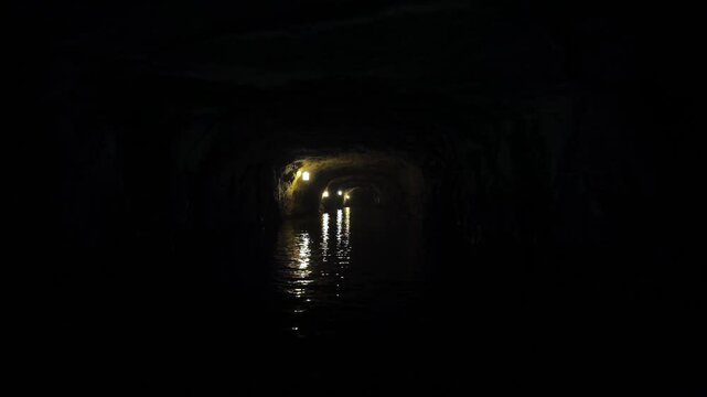 Medieval Asian Dark Cave Water Tunnel With Wall Lights - Boat Passing Underground River in Vietnam
