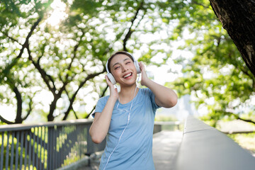 Asian beautiful woman listen to music while standing outdoors in city.