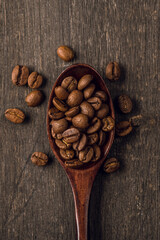 Wooden spoon on the roasted coffee beans on the wooden table. Warm colors background with coffee beans. Shot from above. Shallow depth of field.