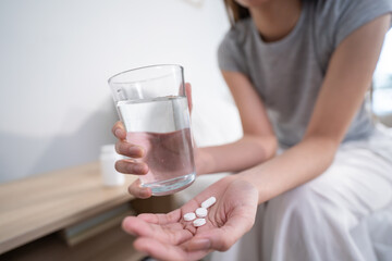 Close up hands of sick woman taking a medicine after wake up on bed. 