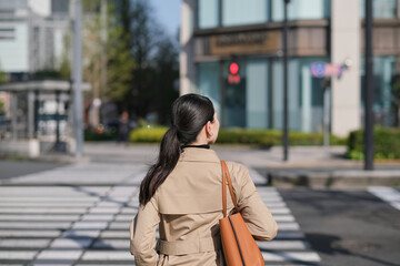 新緑の丸の内を歩くビジネスウーマンの後ろ姿