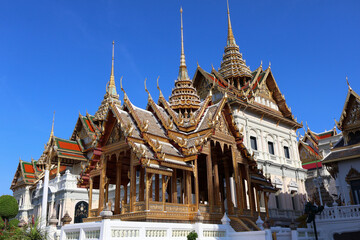 Fototapeta premium Majestic Gilded Thai Royal Pavilion with Ornate Spires Against Blue Sky