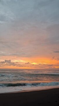 orange sky over the sea with small waves crashing at sunset