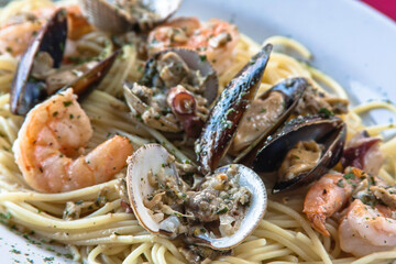 Spaghetti with seafood, clams and mussels served on a white plate on a red background, food