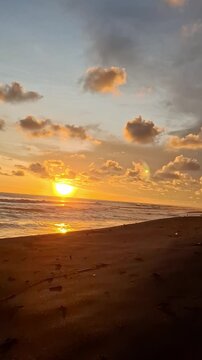 the beauty of the clouds in the orange sky at sunset over the black sand beach