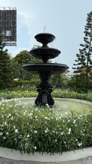 fountain in the garden,water flowing fountain decorating in flower garden,Streams of fountain water with sculpture statue with sun. Close-up of Garden waterfall in pond. Outdoor garden park.Relaxation