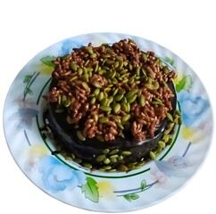 chocolate cake topped with crunchy puffed rice and pumpkin seeds. Served on a floral plate for a beautiful presentation.