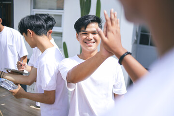Portrait of Asian Volunteer Workers Celebrating Teamwork in Donation Event with High-Five