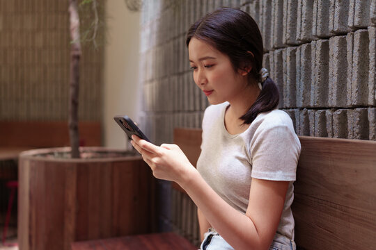Woman enjoying peaceful coffee break while browsing smartphone at cozy outdoor cafe table.