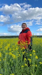 A woman stands among flowers in a field