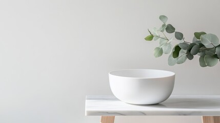 Simple, minimalist bowl on marble table with eucalyptus