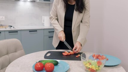 Businesswoman is slicing tomatoes on cutting board, preparing healthy vegetable salad for lunch or dinner in modern kitchen, healthy eating and dieting concept