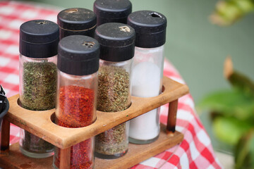 Spice jars on wooden rack at outdoor dining table setting