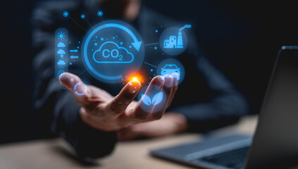 A hand displays digital icons related to carbon emissions, technology, and environmental sustainability, suggesting a focus on climate action and innovation.