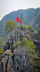 Naklejka premium Vietnam flag with mountain top temple and limestone cliffs