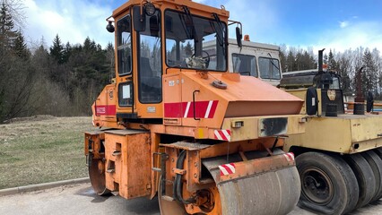 Orange dump truck with red stripes and yellow asphalt paver