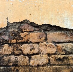 Damaged brick cement wall painted in yellow color