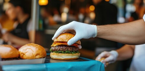 Close-up of gloved hands placing a delicious hamburger on a tray.