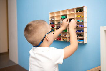 A boy cleans and sorts toy cars into places.