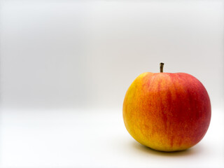 Fresh juicy red apple with yellow spot and stick on top on white background right side of image front view