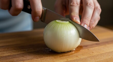 Slicing onion with a knife on a wooden cutting board  