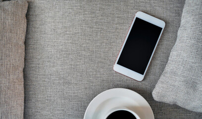 Flat Lay, Top view smartphone mockup and  a cup of black coffee on fabric textile with copy space, digital NOMAD, freelancer workplace or online shopping concept