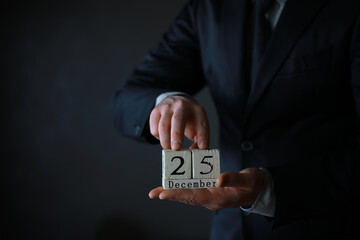 Portrait of  businessman ready for Christmas. Wooden cubes with inscription 25 december