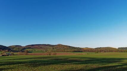 Obraz premium Glenduckie Hill seen from Dunbog Hamlet, with long evening shadows being cast across the fields on a bright April Evening.