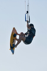 A dynamic photo capturing a kitesurfer in action, riding a wave while performing a maneuver. 