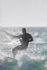 A dynamic photo capturing a kitesurfer in action, riding a wave while performing a maneuver. 
