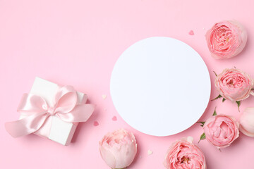 Beautiful pink peony roses with gift box and paper card on color background, space for text