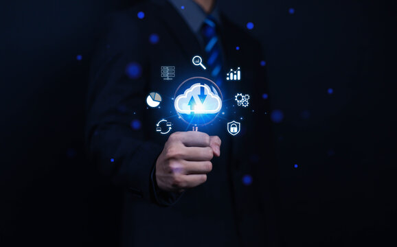 Businessman using magnifying glass to search mobile cloud and cyber security icons. Digital transformation. Cloud computing concept. Internet backup storage. Network and digital.