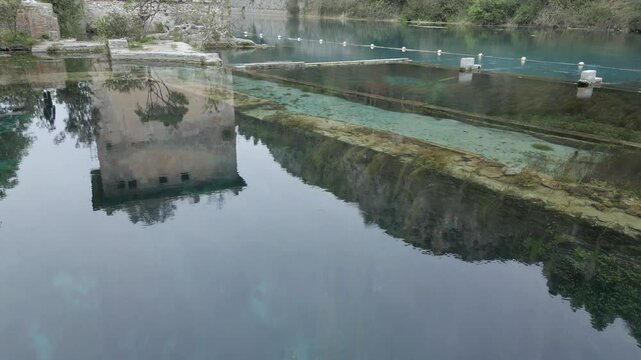 Drone footage of Stifone and the Morica spring in Umbria, Italy: turquoise waters, lush nature, stone ruins, and peaceful river views in a hidden, historic valley.