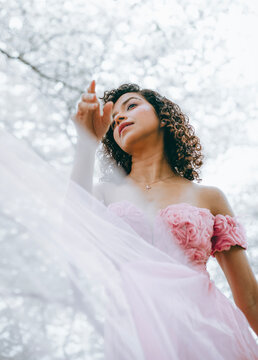 A woman with dark curls in a pink dress