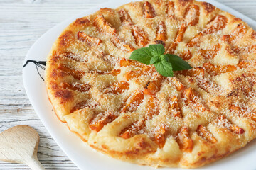 Plate with tasty peach pie on wooden table, closeup view