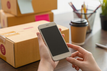 Hand holding smartphone with a blank screen on table, for putting advertising to promote.