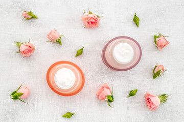 Top view of pink roses and skin care cream with flowers essential oil