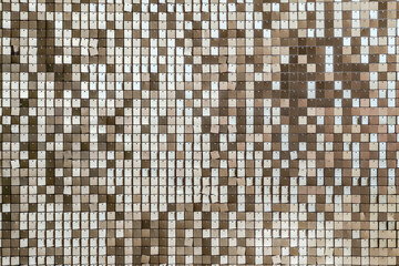An interior wall decorated with golden square tiles resembling fish scales, strung on mesh — ideal as a luxurious, shimmering background for design settings.