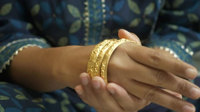 Indian woman wearing 18k hallmarked gold ornament, gold bangles, Closeup