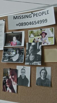 Vertical closeup of cork notice board in refugee shelter or emergency accommodation during war, flood or natural disaster, with photos of missing people and fake hotline or volunteer phone number