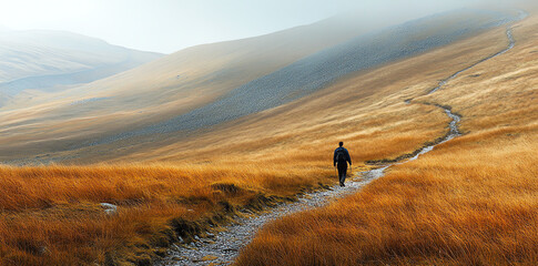 Lone hiker trekking scenic mountain path golden grasses autumn day Perfect for travel adventure and...