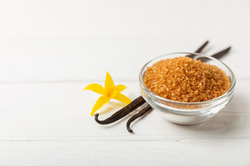 Aromatic vanilla sugar. Vanilla pods. Vanilla sticks, brown and white sugar in a bowl on a textured background. Vanilla flowers, spices and herbs for desserts and baking. Space for text. Copy space